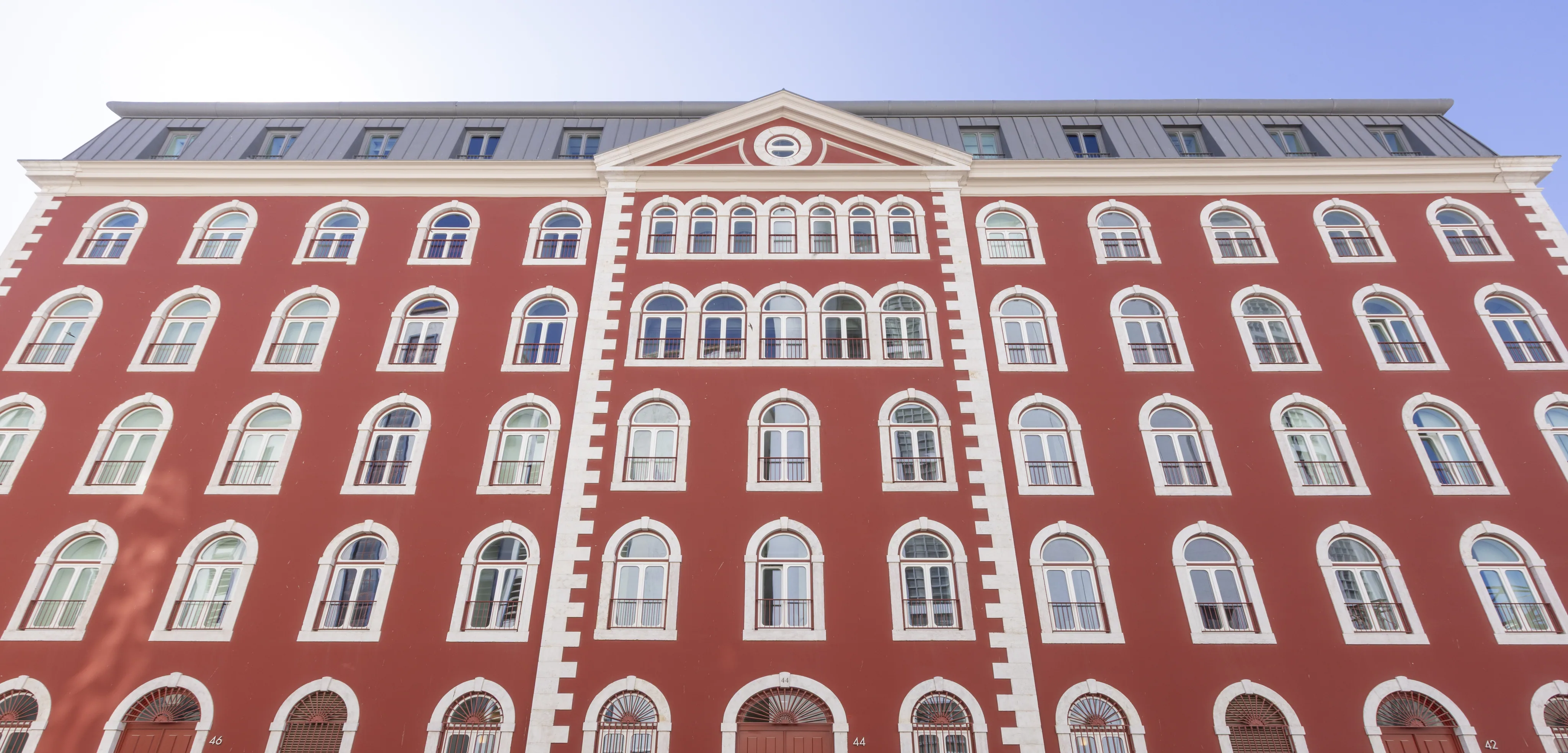 Moagem’s red street façade, with a central pediment, mansard roof and rows of pale stone-framed windows.