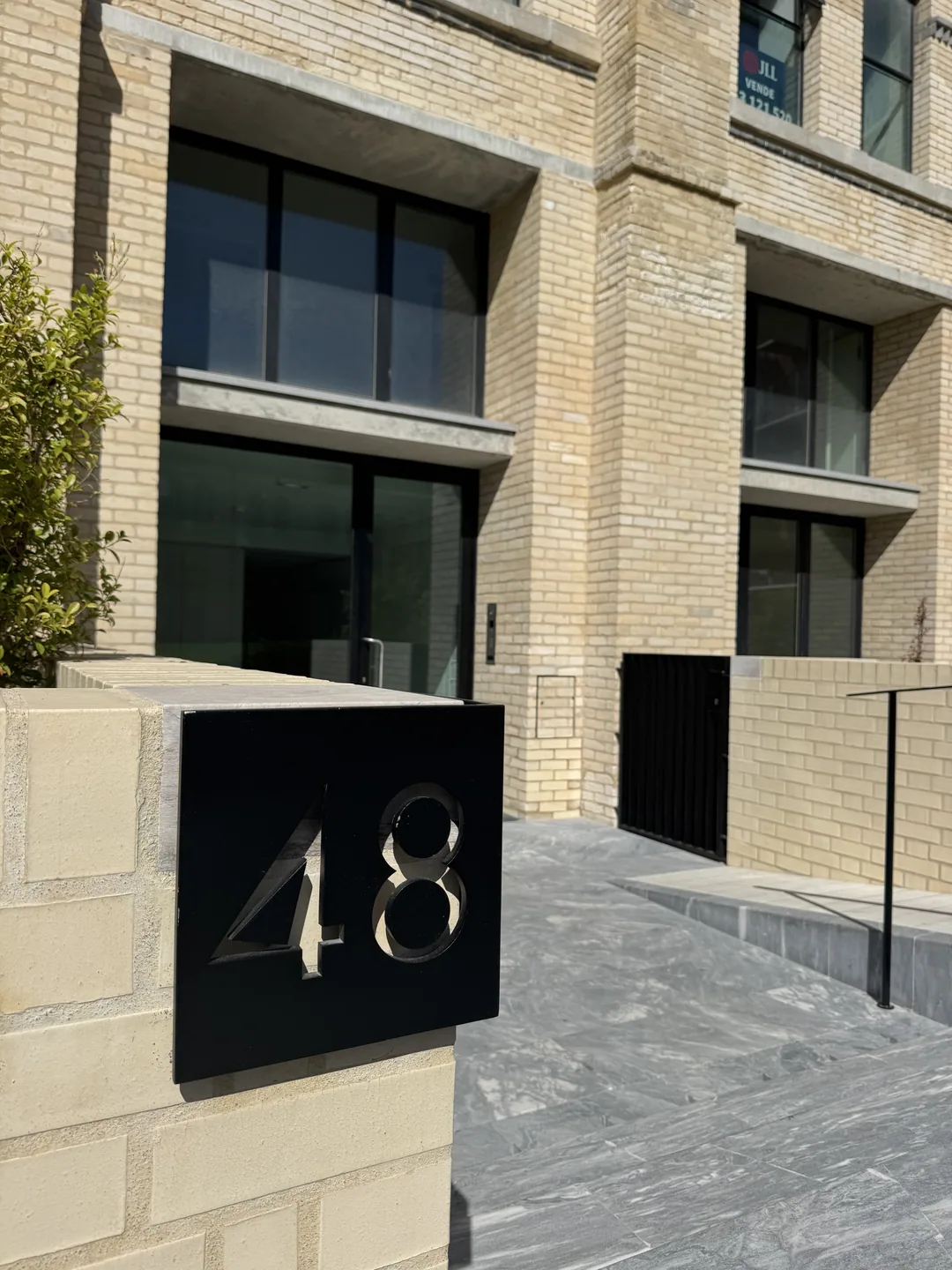 The entrance at Rua do Beato 48: a black number plate on a pale brick wall, glass doors behind a small courtyard.