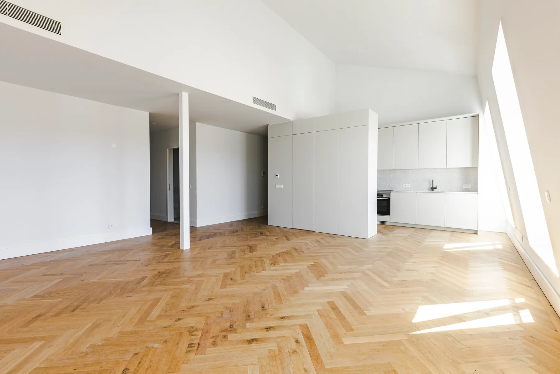 The open living room looking towards the kitchen, with the white column standing in the middle of the room.