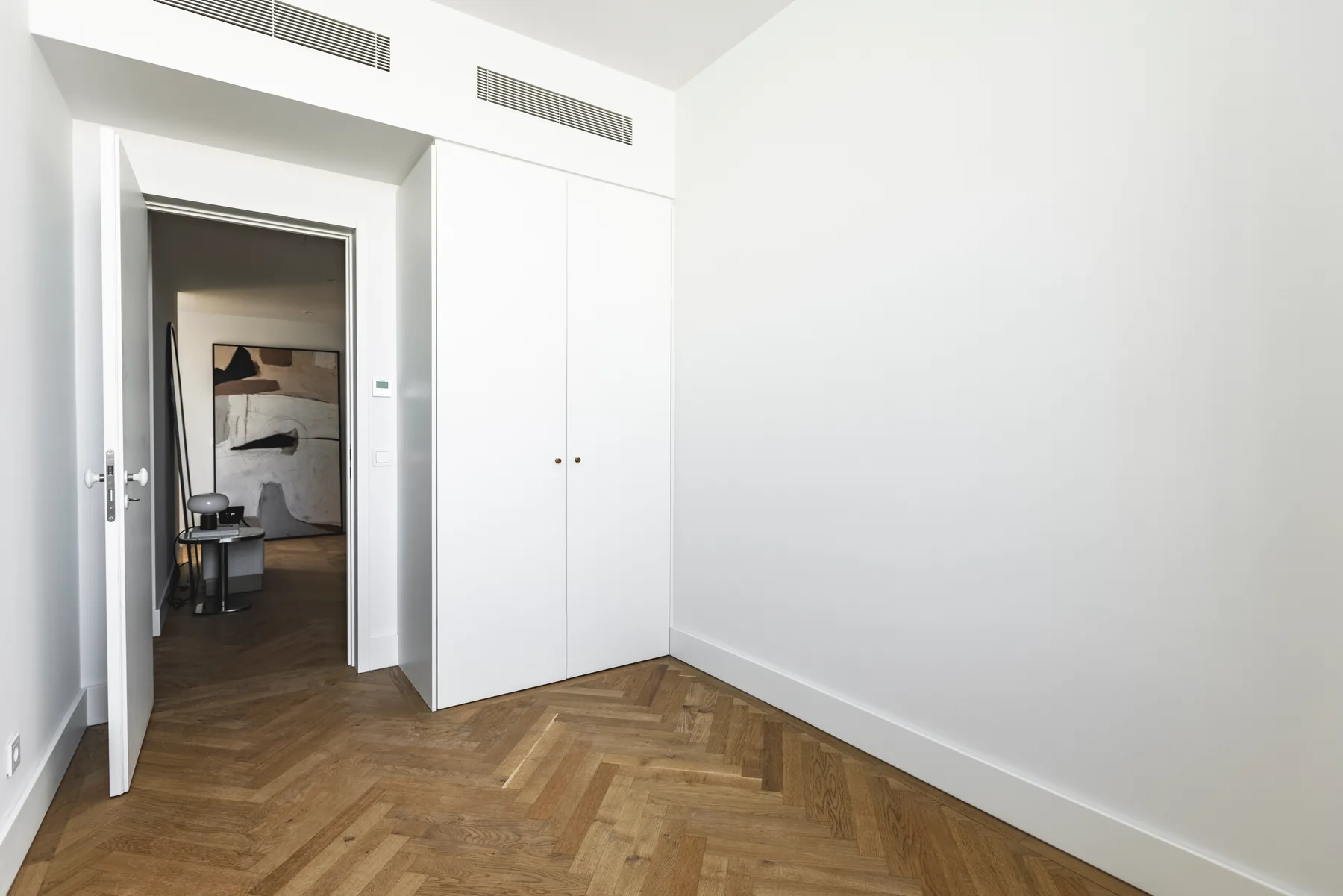 The same bedroom towards the door: a built-in wardrobe beside the open door to the corridor.